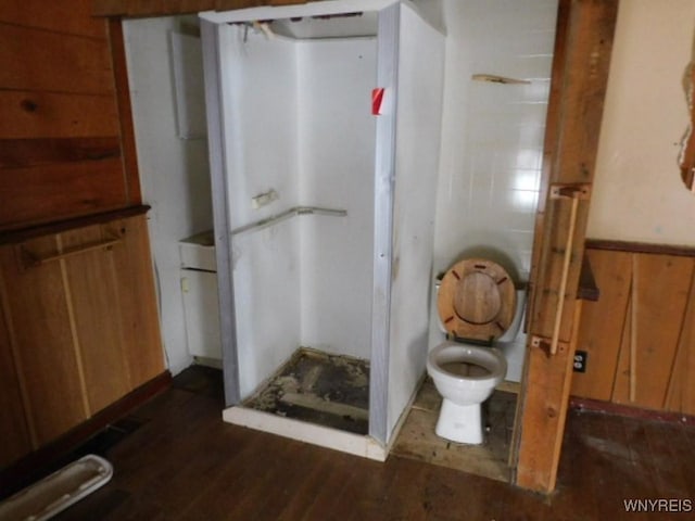 bathroom with a wainscoted wall, wood walls, wood finished floors, and toilet