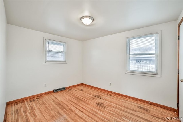 spare room with visible vents, light wood-style flooring, and baseboards