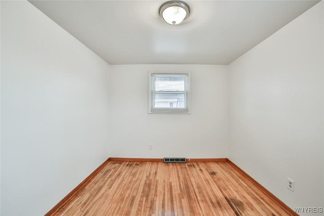 spare room with light wood-style flooring, visible vents, and baseboards