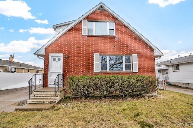 view of front of house with a front yard, brick siding, and fence