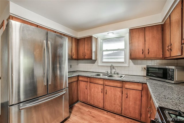 kitchen featuring stainless steel appliances, brown cabinets, a sink, and decorative backsplash