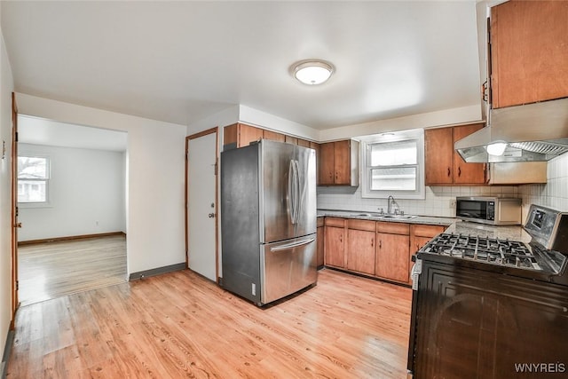 kitchen featuring plenty of natural light, decorative backsplash, stainless steel appliances, under cabinet range hood, and a sink