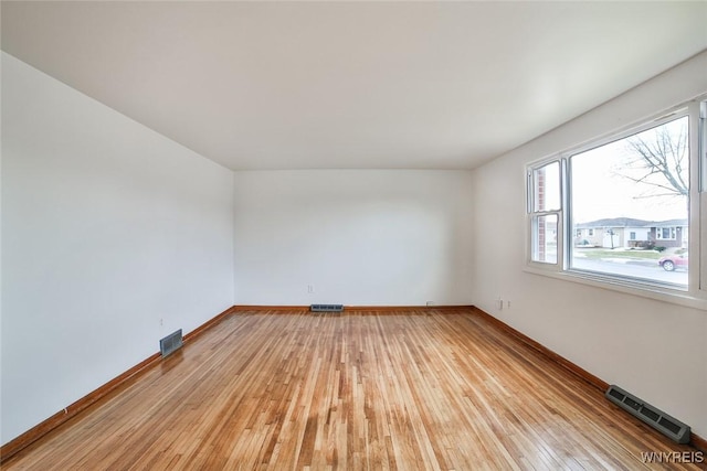 empty room with visible vents, light wood-style flooring, and baseboards