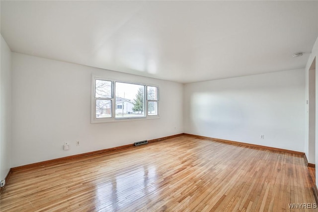 empty room with light wood-type flooring, baseboards, and visible vents