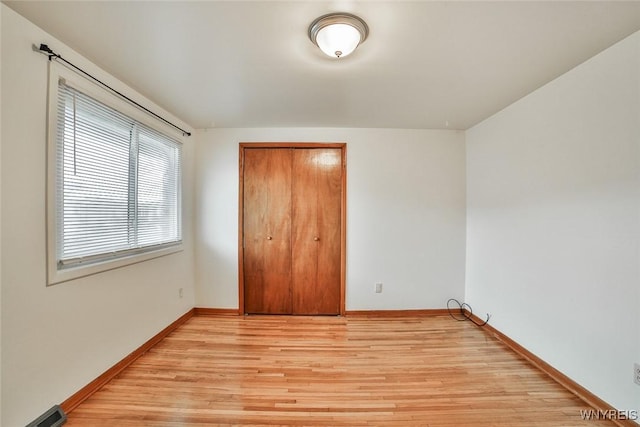 unfurnished bedroom featuring visible vents, a closet, light wood-style flooring, and baseboards