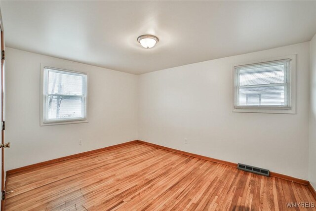 spare room featuring light wood-style flooring, visible vents, and baseboards