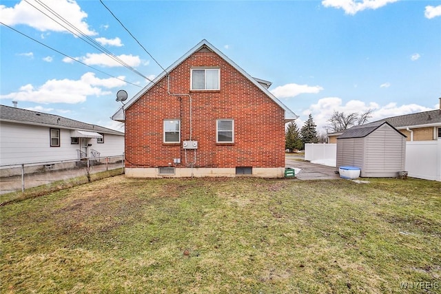 back of house with a fenced backyard, a storage shed, brick siding, an outdoor structure, and a yard