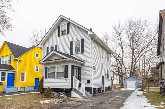 view of front of home with entry steps, an outbuilding, a detached garage, fence, and driveway