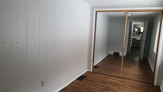 hallway with dark wood-style floors, visible vents, and baseboards