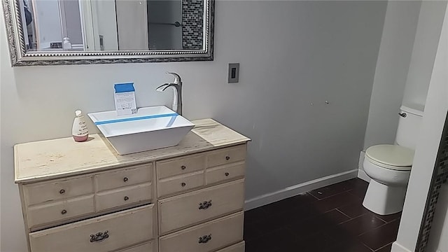 half bath featuring baseboards, vanity, and toilet