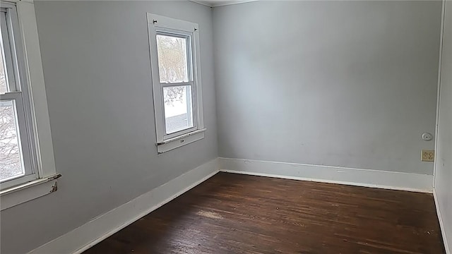 spare room featuring dark wood finished floors and baseboards