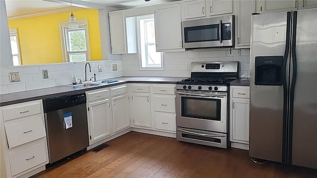 kitchen featuring tasteful backsplash, dark wood-style floors, appliances with stainless steel finishes, crown molding, and a sink