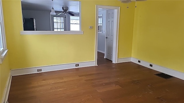 spare room featuring ceiling fan, wood finished floors, visible vents, and baseboards