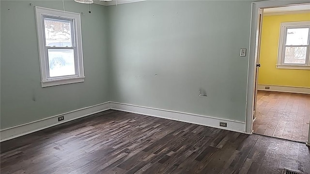 unfurnished room with dark wood-style flooring, baseboard heating, and baseboards