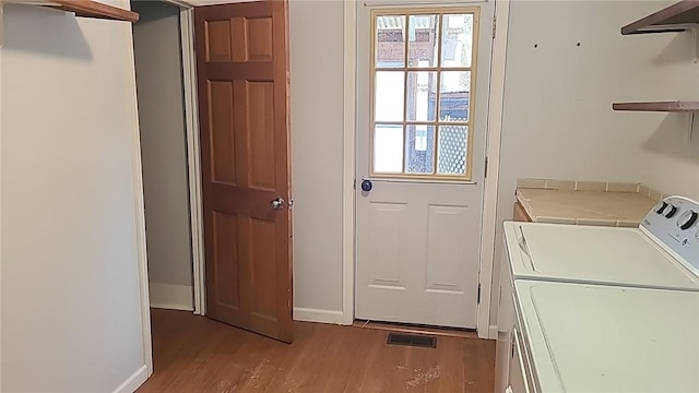 laundry room with laundry area, wood finished floors, plenty of natural light, and separate washer and dryer