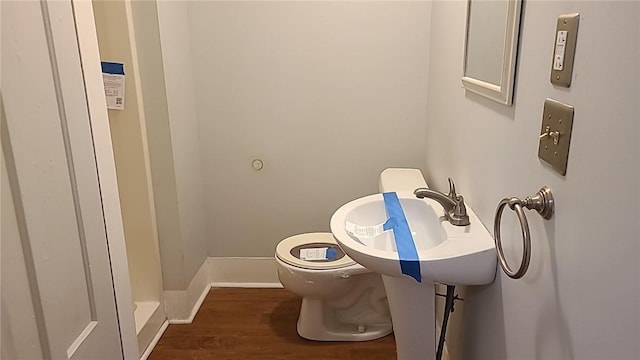 bathroom with toilet, a sink, baseboards, and wood finished floors