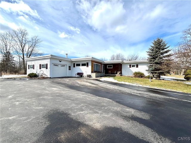 ranch-style home featuring a garage and aphalt driveway