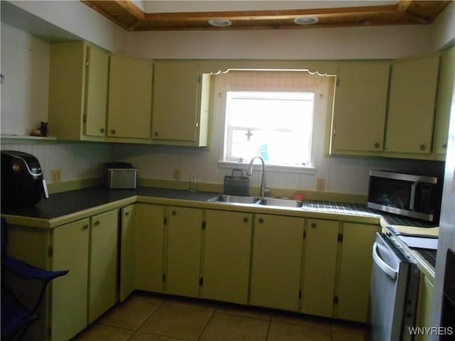 kitchen featuring range, stainless steel microwave, a sink, and light tile patterned flooring