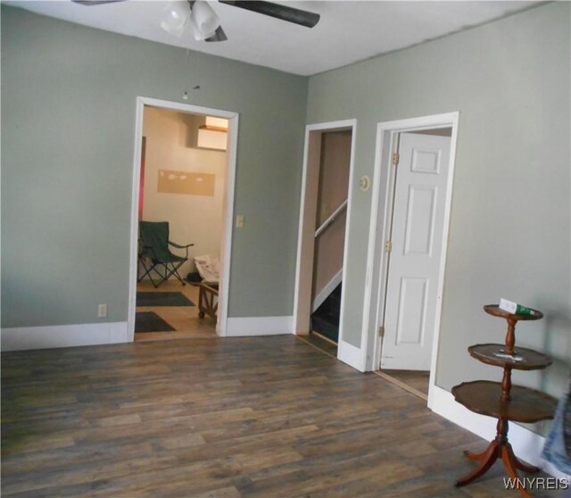 spare room featuring stairway, ceiling fan, baseboards, and wood finished floors