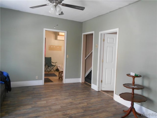 empty room featuring a ceiling fan, baseboards, and wood finished floors