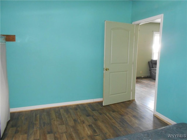 unfurnished bedroom with dark wood finished floors and baseboards