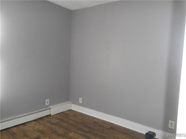 unfurnished room with a baseboard heating unit, dark wood-style flooring, and baseboards