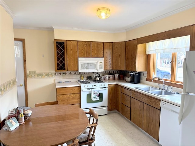 kitchen with brown cabinets, light countertops, ornamental molding, a sink, and white appliances