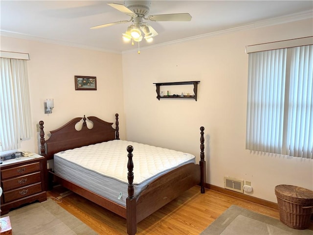 bedroom featuring light wood-style floors, visible vents, crown molding, and baseboards