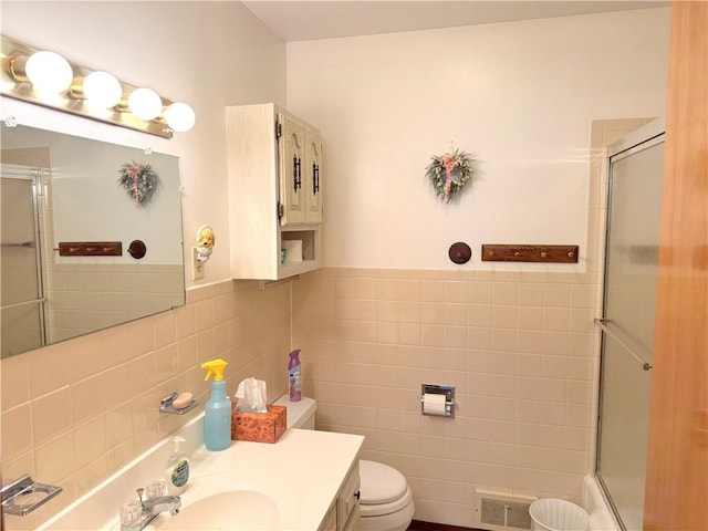 full bathroom featuring toilet, visible vents, an enclosed shower, and tile walls