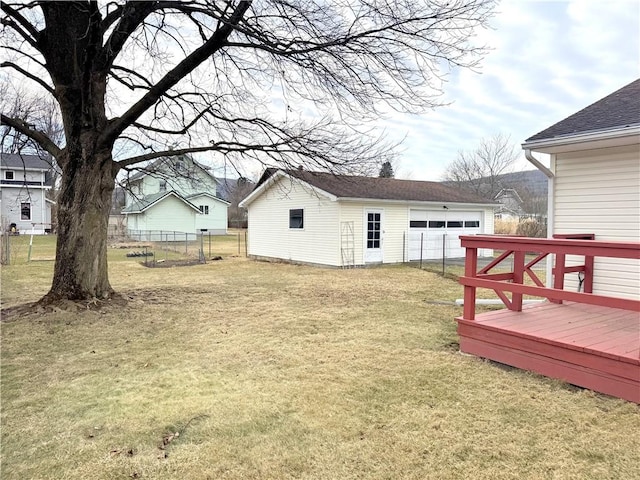 rear view of property with a garage, a lawn, an outbuilding, fence, and a deck