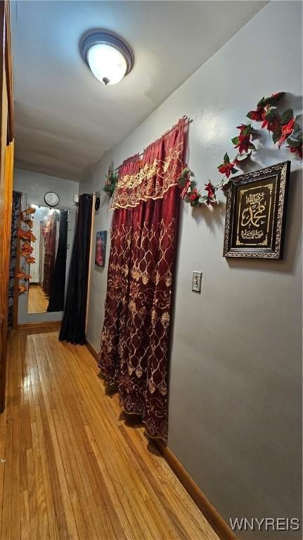 hallway featuring light wood finished floors and baseboards