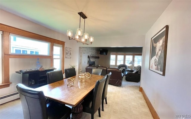 dining area featuring a chandelier, a baseboard heating unit, and baseboards