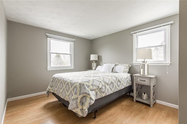 bedroom with multiple windows, baseboards, and wood finished floors