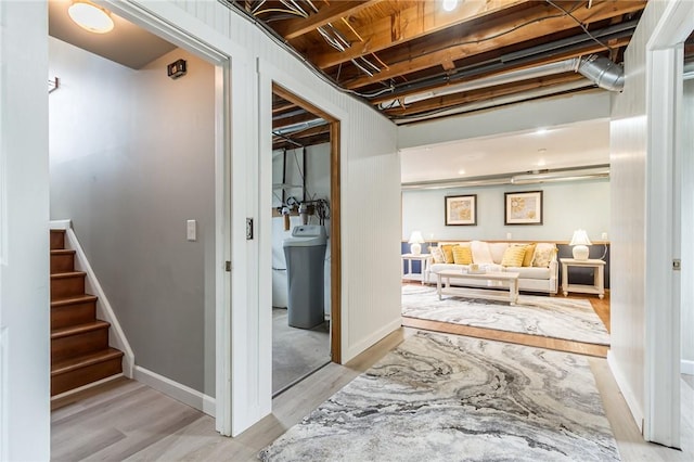 hall featuring stairs, baseboards, and light wood-style floors