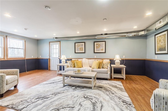 living room with recessed lighting, wood finished floors, and wainscoting