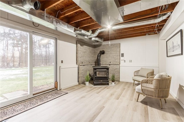 living area with a wood stove, a healthy amount of sunlight, and wood finished floors