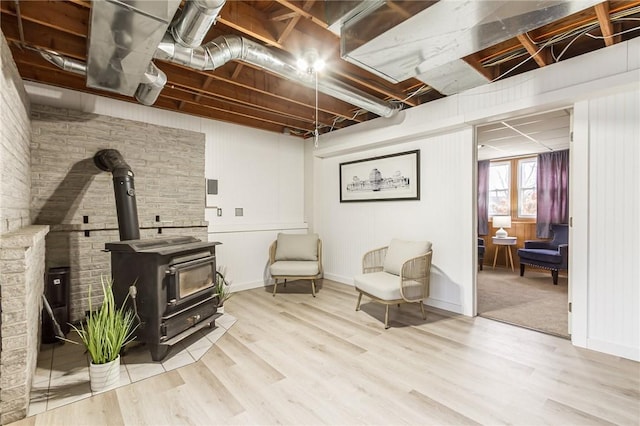 living area with a wood stove, baseboards, and wood finished floors