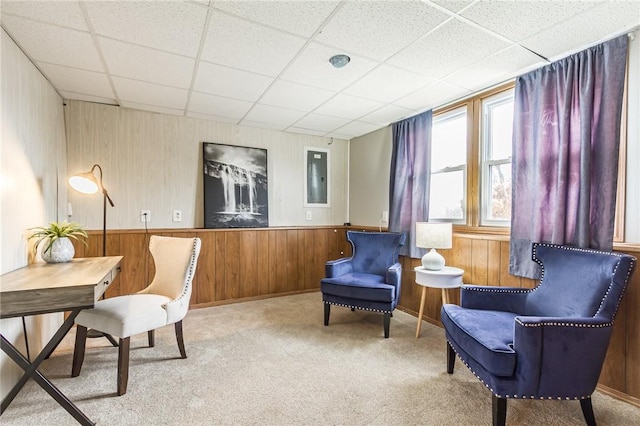 sitting room featuring carpet floors, a paneled ceiling, a wainscoted wall, and wood walls