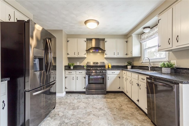 kitchen with a sink, white cabinets, wall chimney range hood, appliances with stainless steel finishes, and dark countertops