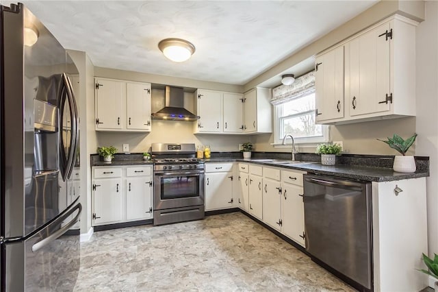 kitchen with stainless steel appliances, a sink, white cabinets, wall chimney exhaust hood, and dark countertops