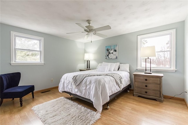 bedroom with baseboards, a ceiling fan, visible vents, and light wood-style floors