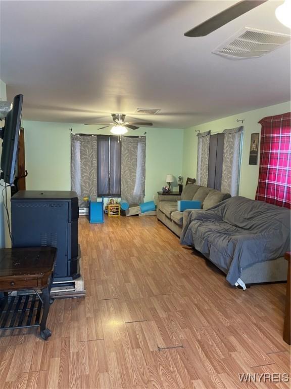 living area featuring ceiling fan, visible vents, and wood finished floors