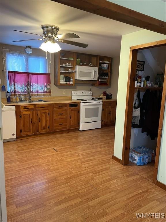 kitchen with white appliances, brown cabinets, light countertops, light wood-type flooring, and a sink