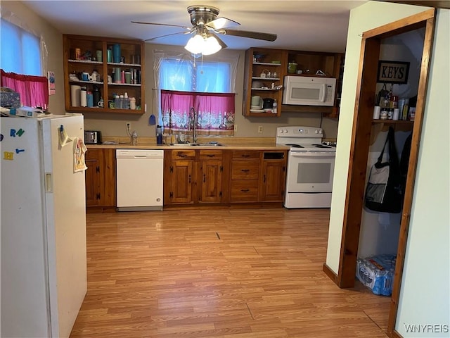 kitchen with light wood finished floors, open shelves, white appliances, and a sink