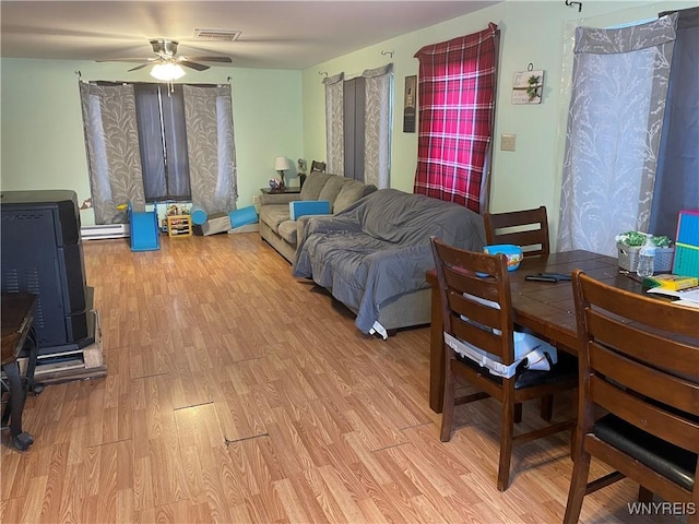 living room featuring light wood-style floors, a baseboard radiator, visible vents, and ceiling fan