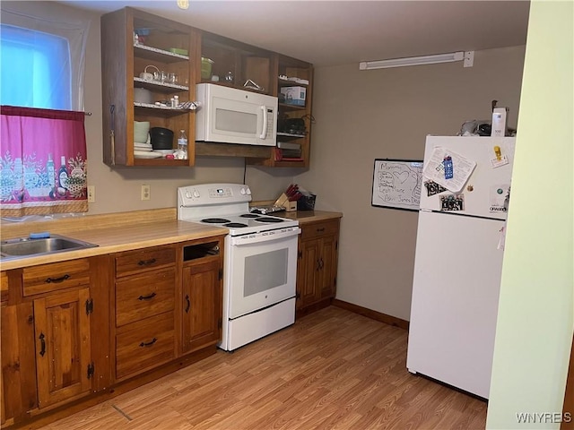 kitchen featuring white appliances, brown cabinetry, light wood-style flooring, light countertops, and a sink