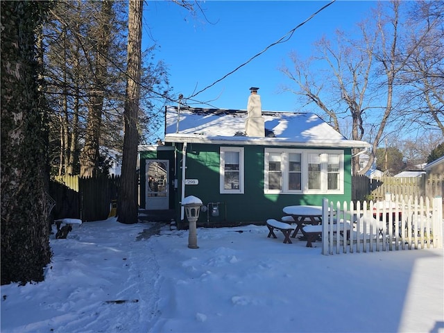 snow covered property with a chimney and fence