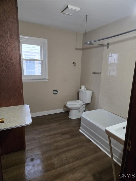 bathroom featuring tub / shower combination, baseboards, toilet, and wood finished floors