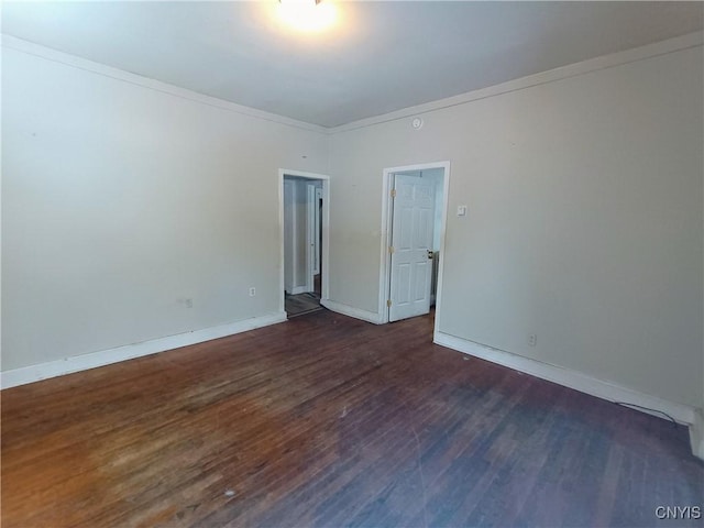 empty room with baseboards, ornamental molding, and dark wood-style flooring