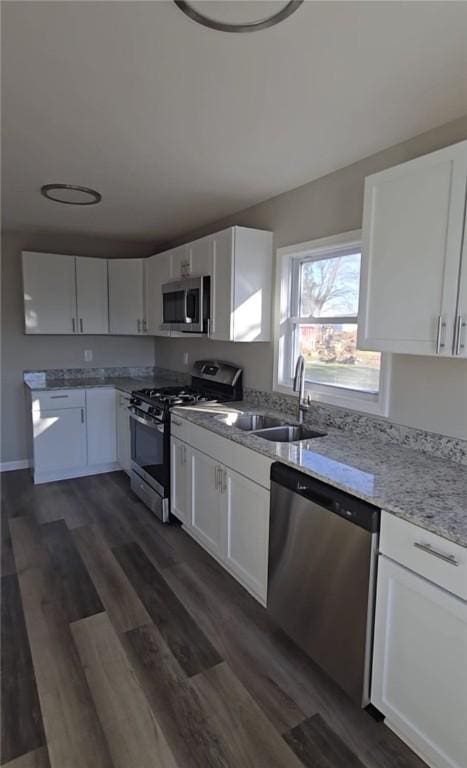 kitchen with light stone counters, appliances with stainless steel finishes, dark wood finished floors, and white cabinetry